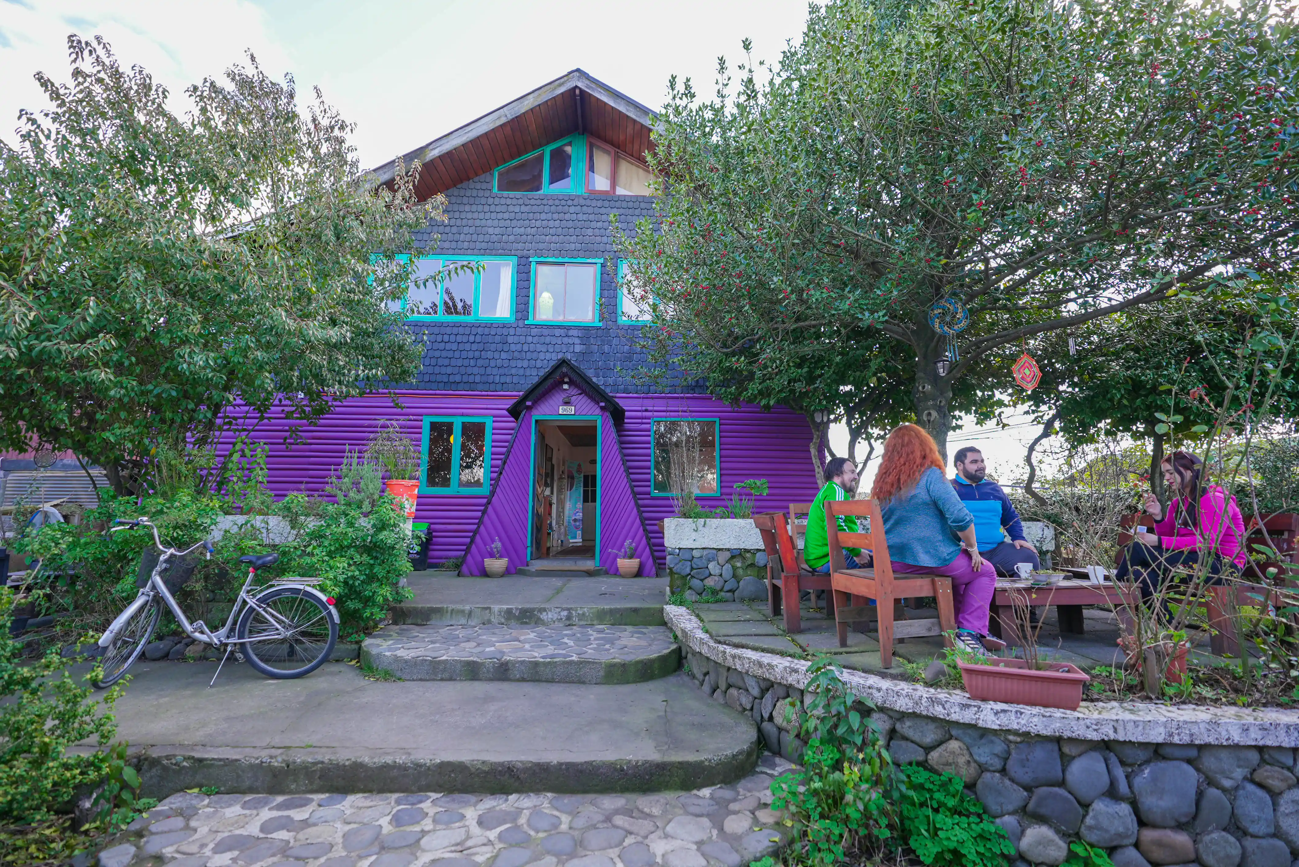 La entrada del hostal muestra su singular fachada y un ambiente relajado, con un cielo claro que aporta calidez a la escena. - Hostal Micelio, Villarrica